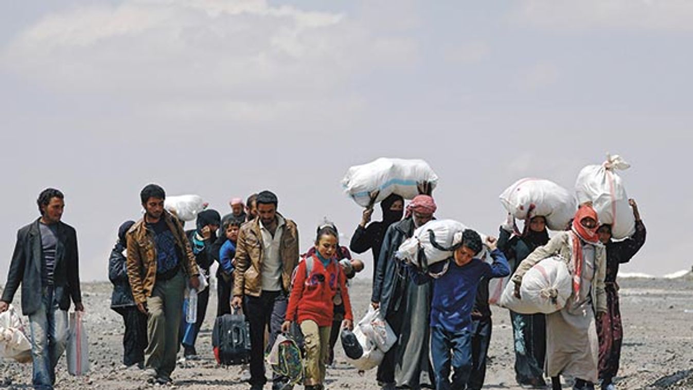 Internally displaced people who fled Raqqa city carry their belongings as they leave a camp in Ain Issa
