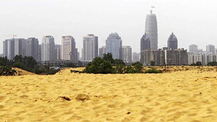 Sand is piled up on the outskirts of Zhengzhou as the central business district of the city is seen in the background, in Zhengzhou