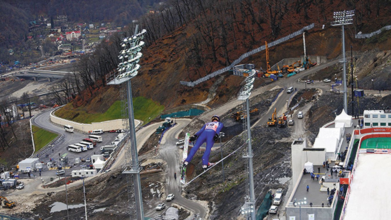 A trial jumper soars over construction sites surrounding the ski jumping hill of Krasnaya Polyana