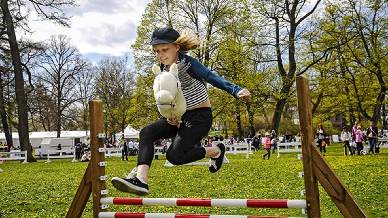 Girl jumps over a hobby horsing fence during Finland 100 equestrian event in Helsinki