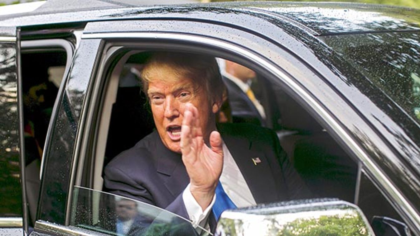 Businessman and Republican presidential candidate Donald Trump waves from his SUV after a back-yard reception in Bedford