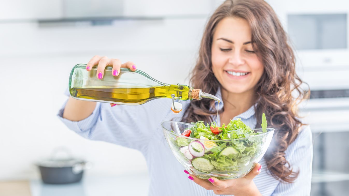 Young,Woman,Pouring,Olive,Oil,In,To,The,Salad.,Healthy