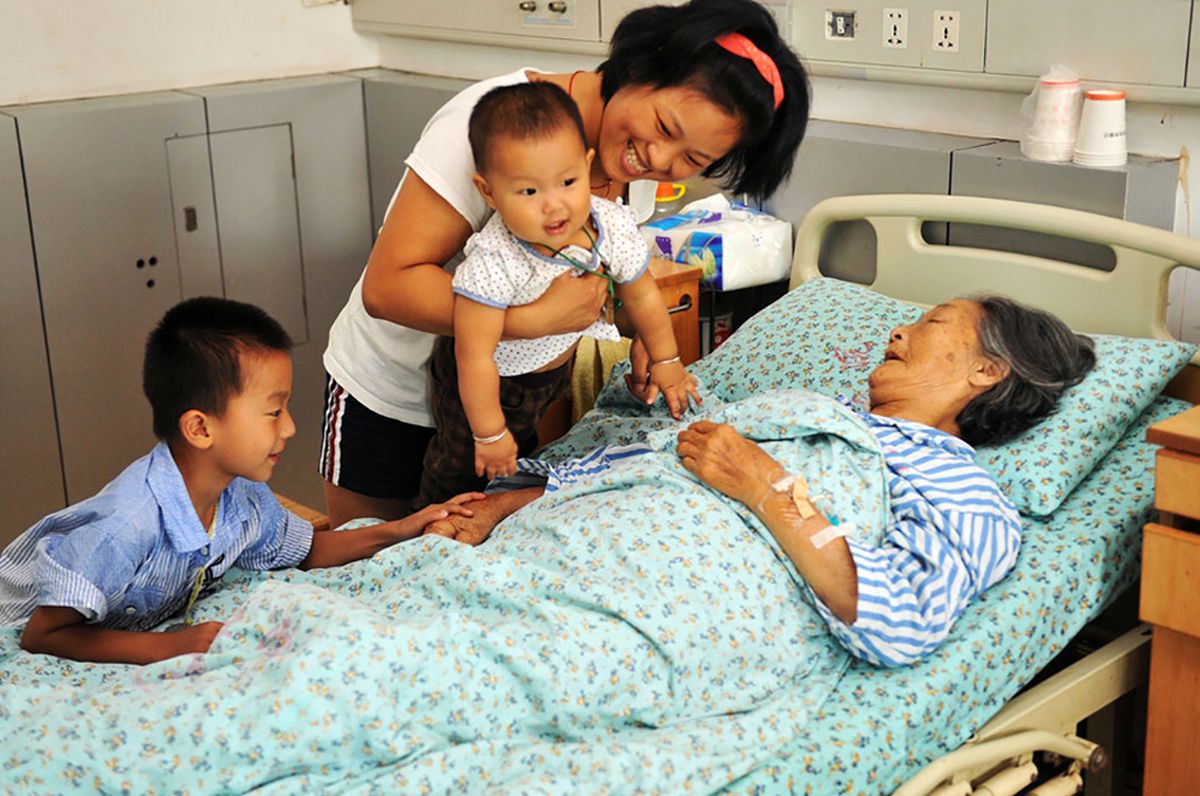 Image: Lou Xiaoying, right, lies in the hospital with one of her daughters, center.