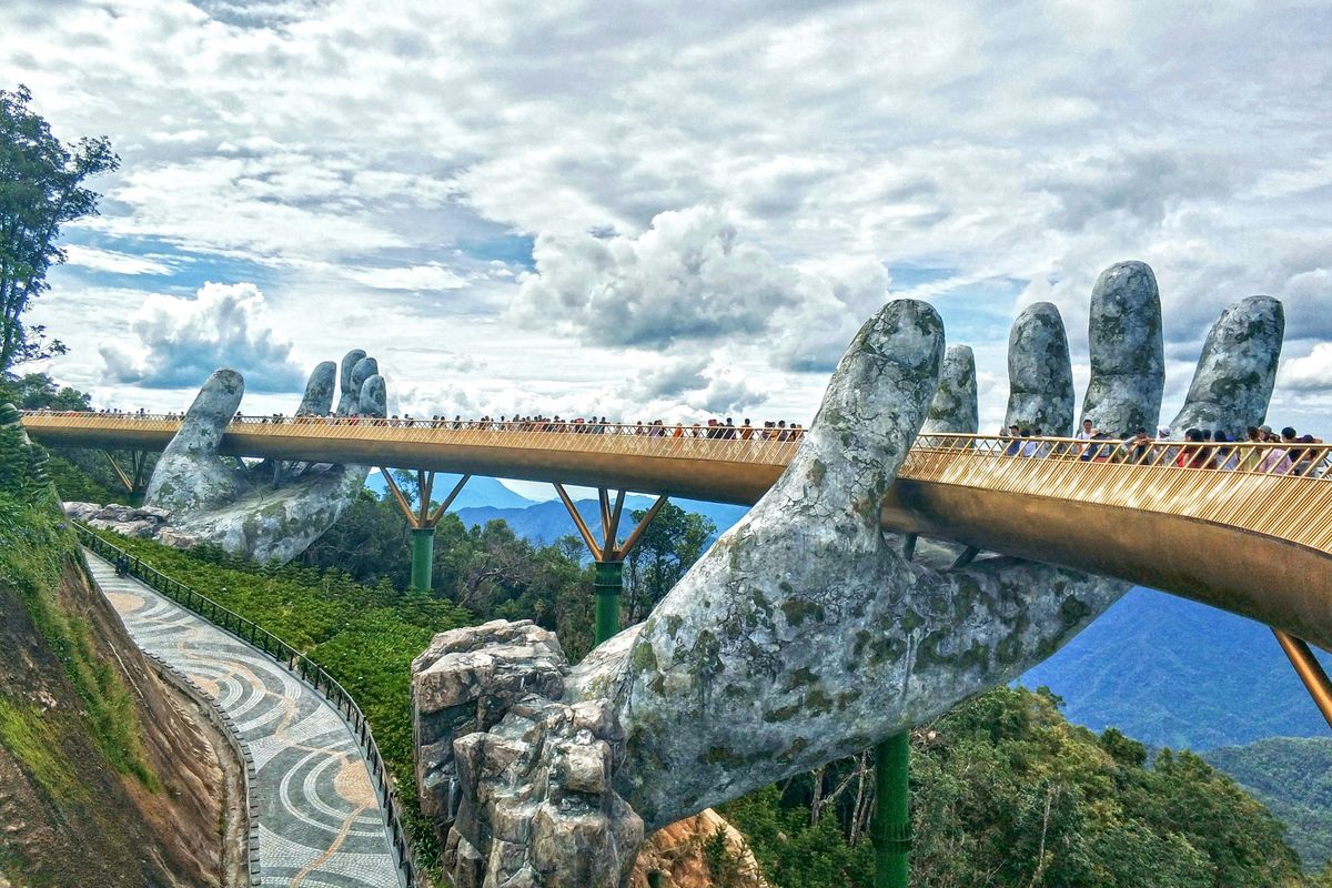 Golden Bridge held up by hand statues embraced by mist and clouds in Da Nang