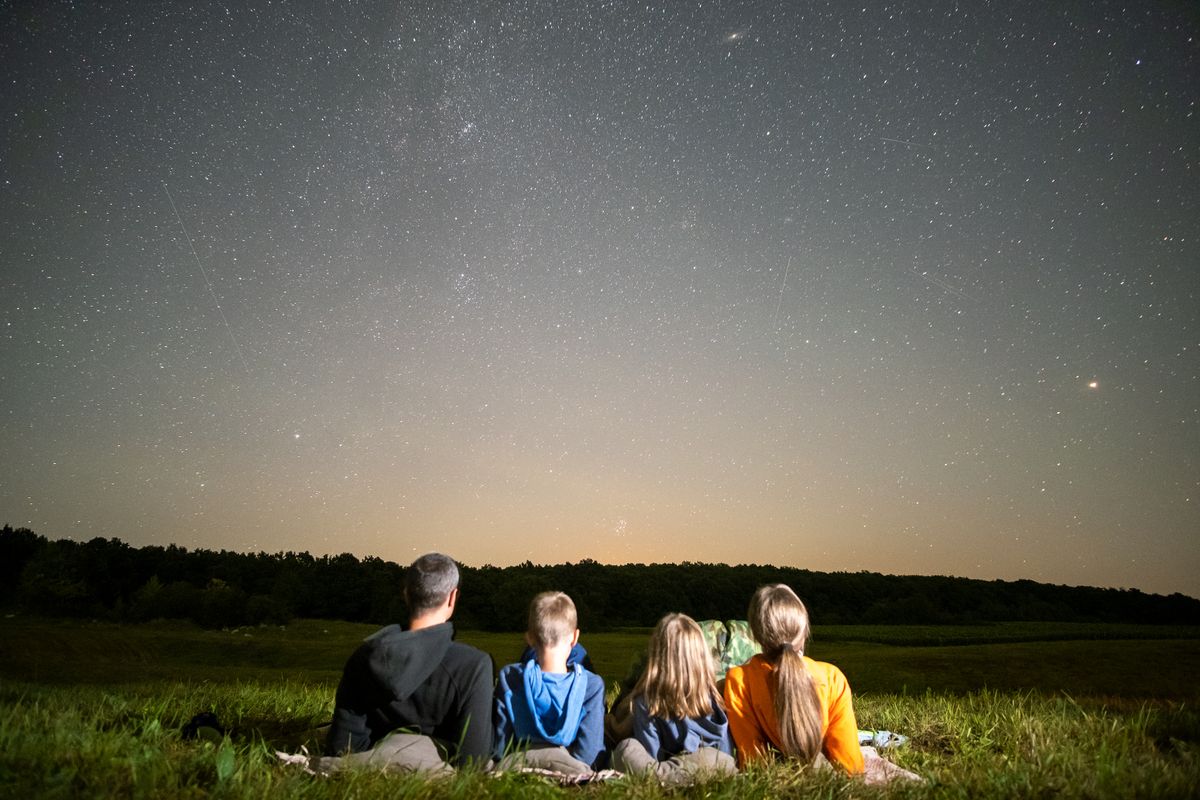 Happy,Family,Resting,In,Night,Field,Looking,At,Dark,Sky