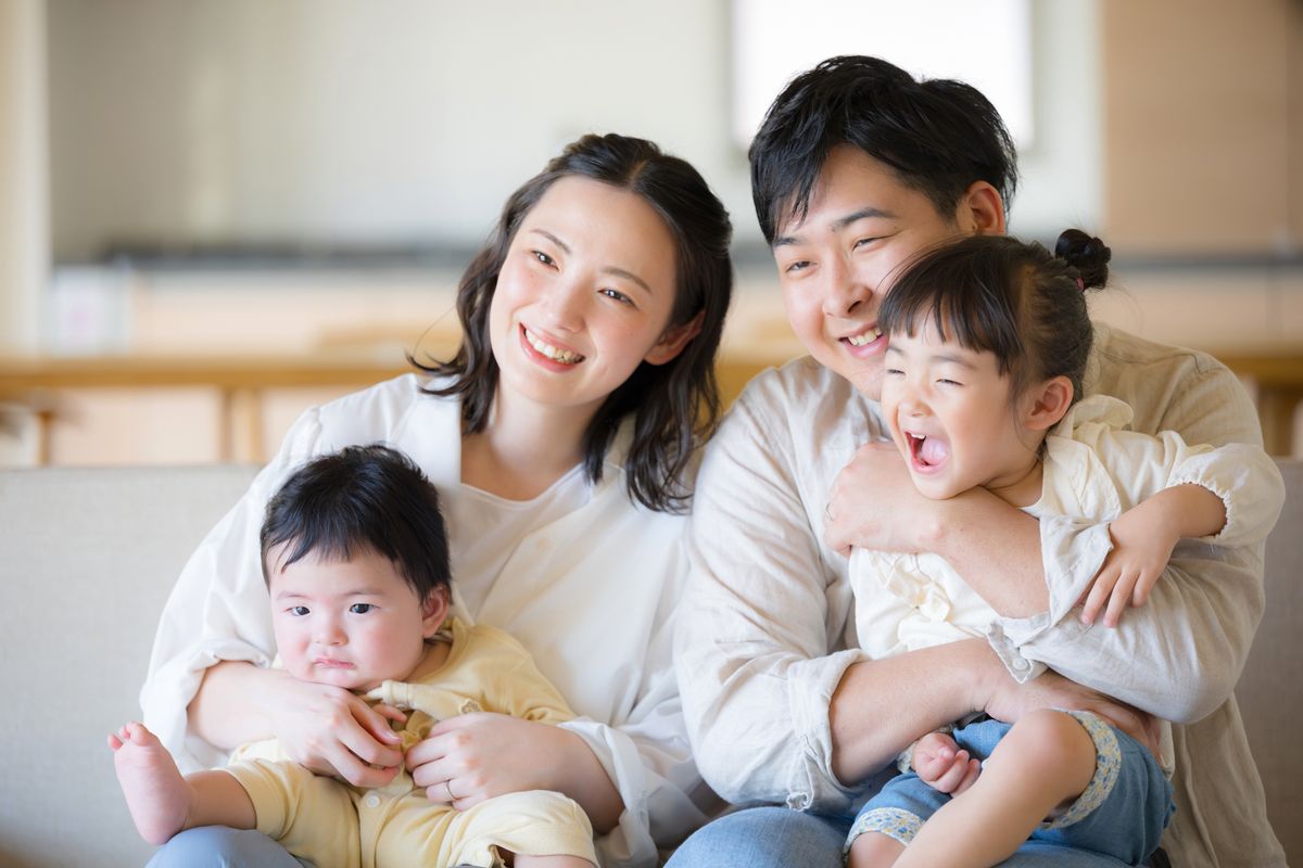 Happy,Japanese,Family,Of,Four,Relaxing,On,A,Sofa,In