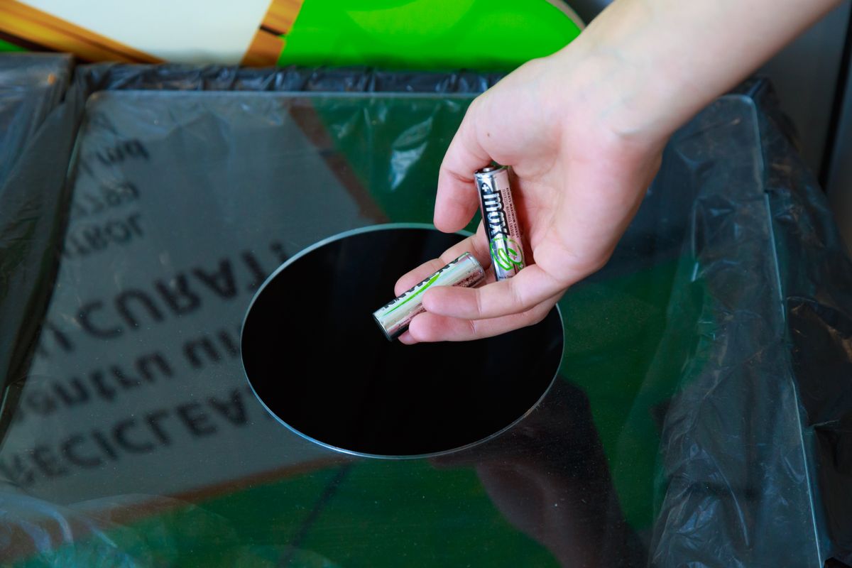 Womans,Hand,Throws,The,Batteries,Into,A,Special,Trash,Can